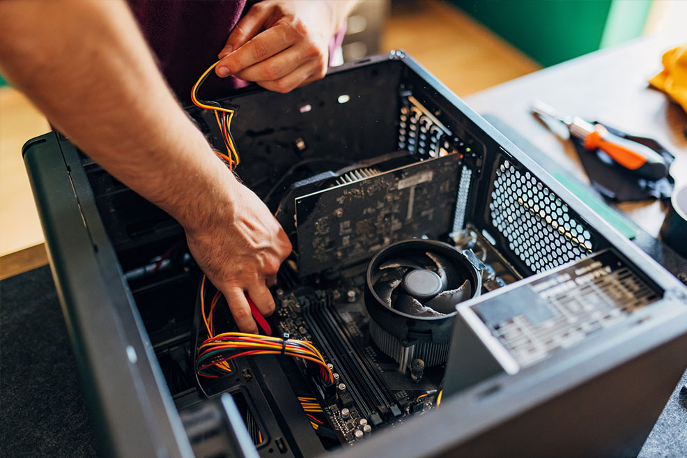 Technician assembling computer components, focusing on wiring inside a desktop PC case, showcasing hardware repair services offered by Bizup.