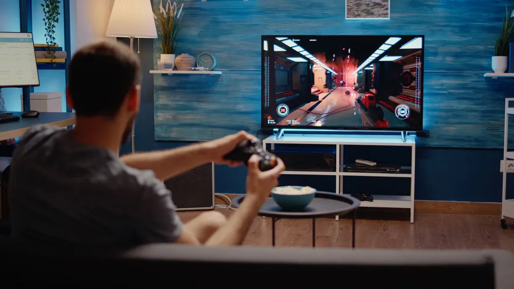 Person playing video game on TV with gaming console, showcasing home gaming setup and console usage.