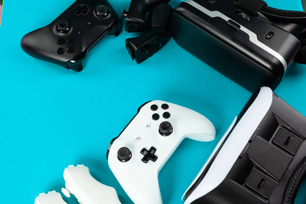 Gaming controllers and VR headset on a turquoise background, representing expert gaming console repairs at Bizup in Murray Bridge.