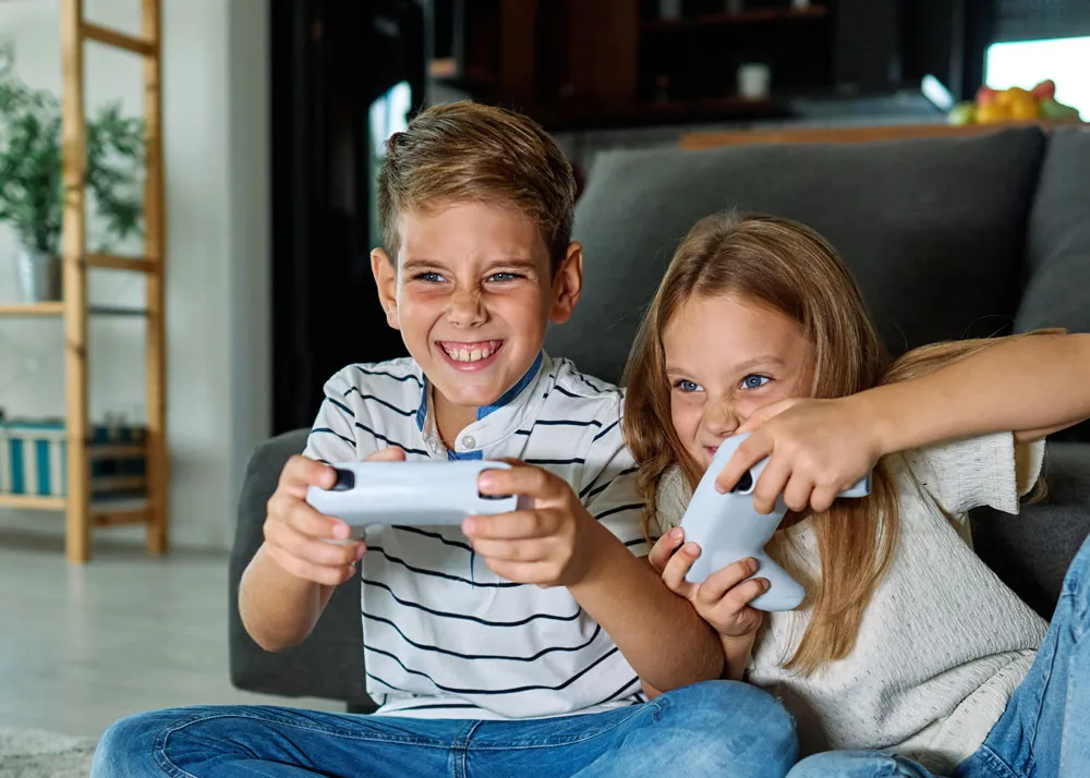 Children playing video games with gaming controllers, showcasing excitement and engagement in a living room setting, relevant to gaming console repair services in Broken Hill.