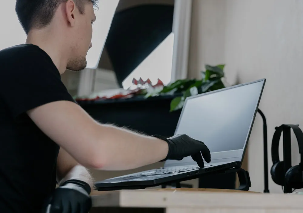Technician wearing gloves working on laptop in a clean environment, emphasizing computer repair and virus removal services in Broken Hill.