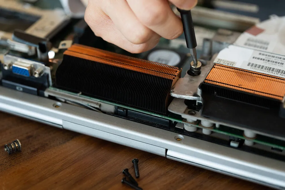 Hand repairing a laptop's internal components, showcasing expert computer repair services relevant to virus removal and malware solutions in Broken Hill.