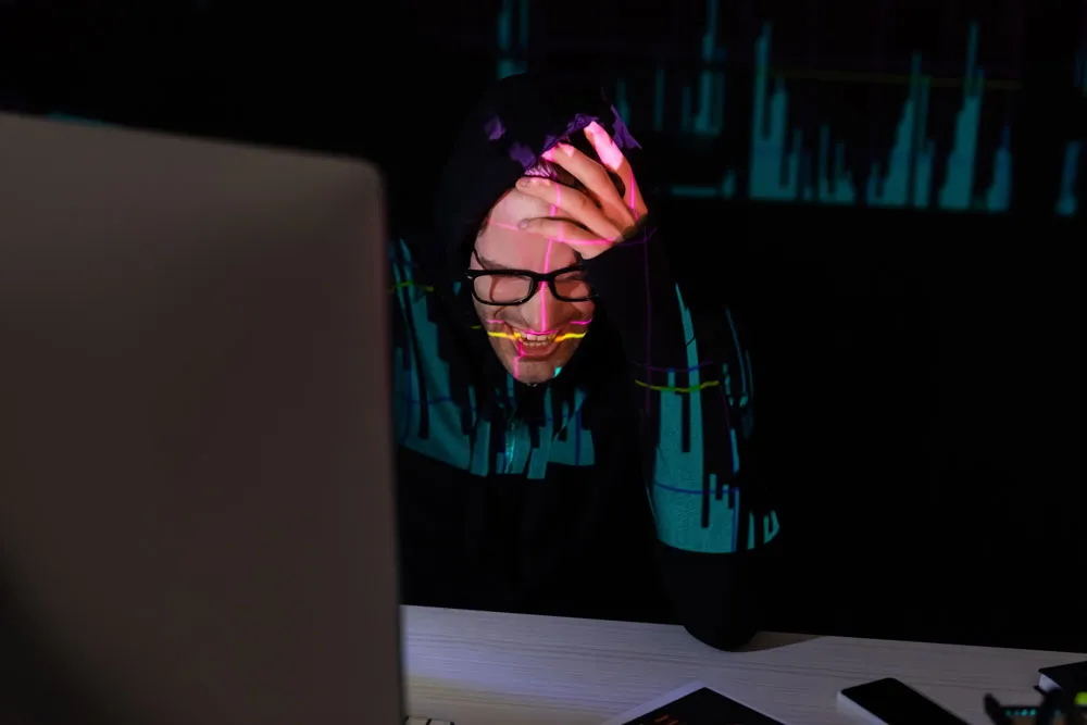 Person in a hoodie with glasses showing frustration while looking at a computer screen, representing the stress of computer issues and the need for virus cleaning services in Murray Bridge.